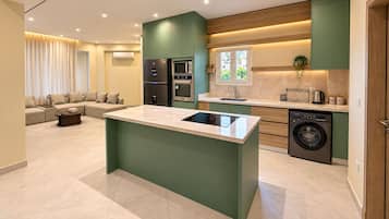 A modern kitchen with a central island, built-in appliances, and a dining area with a sofa.