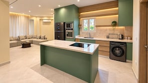 A modern kitchen with a central island, built-in appliances, and a dining area with a sofa. - NOMA Mohandessin (Giza Governorate)