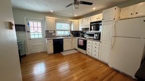 A kitchen with white cabinets, a black stove, and a refrigerator. - 3-bedroom house in South Boston on a quiet side street, steps from everything (Boston)