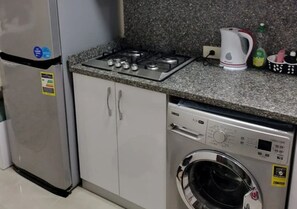 A kitchen with a stainless steel refrigerator, a built-in stove, and a front-loading washing machine. - Pool View Studio Tiba Golden Resort (Hurghada)