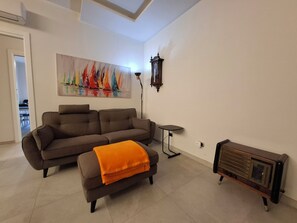 Ein Wohnzimmer mit einer Couch, einem Hocker und einem Vintage-Radio.