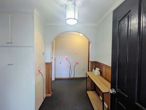 A hallway with a wooden bench, a black door, and a white cabinet. - Makers Rest a relaxing 4BR 3Bath for 6 with its own Poolfresh Wellness Retreat (Wynyard)
