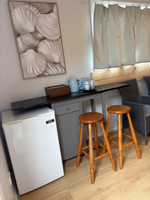 A compact kitchenette with a refrigerator, a coffee maker, and two stools. - Makers Rest a relaxing 4BR 3Bath for 6 with its own Poolfresh Wellness Retreat (Wynyard)