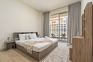 Ein modernes Hotelzimmer mit einem großen Bett, einem Nachttisch, einer digitalen Uhr und Blick auf die Stadt durch große Fenster.