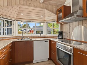 A kitchen with wooden cabinets, a dishwasher, an oven, and a coffee maker. - "Erikgine" - 900m from the sea by Interhome (Væggerløse)