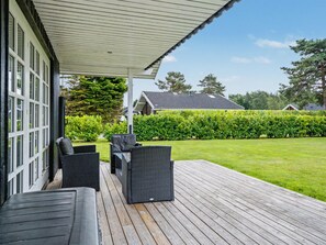 A covered outdoor seating area with wicker furniture and a view of a well-maintained lawn and hedge. - "Erikgine" - 900m from the sea by Interhome (Væggerløse)