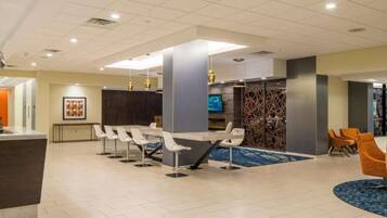 A hotel lobby with a reception desk, seating area, and a TV screen.