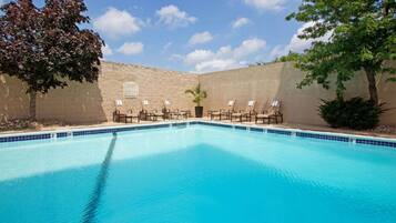 A swimming pool with lounge chairs and a brick wall.