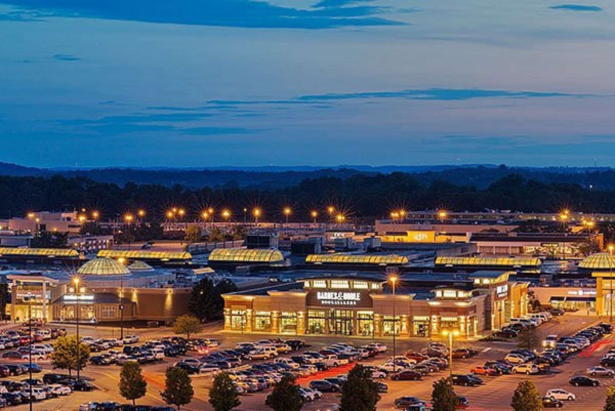 A large parking lot with multiple buildings, including a shopping center with a prominent sign.