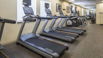 Varias caminadoras con la etiqueta MATRIX en un gimnasio con piso alfombrado e iluminación en el techo.