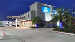 A hotel with a prominent 'Haven Inn & Suites' sign, a covered parking area, and a palm tree. - Downtown Stay + Free Breakfast & Parking (Houston)
