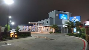 Hotel amb un gran rètol, una zona de pàrquing coberta i una entrada tancada per una reixa.