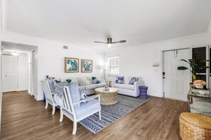 A living room with a white sofa, a blue armchair, a round coffee table, and a ceiling fan. - Harbour Lakes of Naples (Naples)