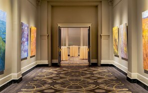 A hallway with a patterned carpet leading to a room with a large window and a door. - Near James River + Rooftop Restaurant & Gym (Lynchburg)