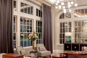 A room with large windows, a chandelier, and a vase of flowers. - Near James River + Rooftop Restaurant & Gym (Lynchburg)