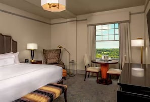 A hotel room with a bed, a desk, a chair, a table, and a view of the outdoors. - Downtown Lynchburg + On Site Dining & Gym (Lynchburg)