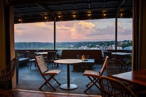 An outdoor seating area with tables and chairs, a fire feature, and a view of the landscape. - Downtown Lynchburg + On Site Dining & Gym (Lynchburg)