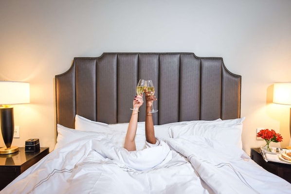 A bed with a headboard, white bedding, and two bedside lamps. - Downtown Lynchburg + On Site Dining & Gym (Lynchburg)