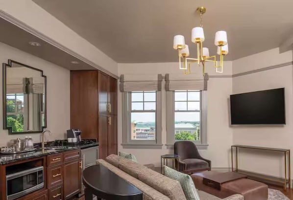 A modern living room with a sofa, a coffee table, a TV, and a fireplace. - 1BR King Steps to James River + Dining (Lynchburg)