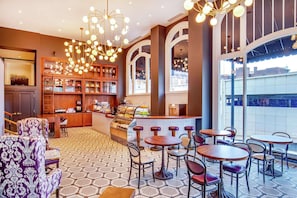 A cafe with hexagonal patterned flooring, wooden shelves with various items, and a bar area with stools. - 1BR King Steps to James River + Dining (Lynchburg)