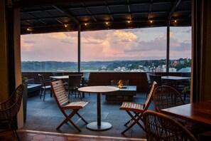 An outdoor seating area with tables and chairs, a fire feature, and a view of the landscape. - 1BR King Steps to James River + Dining (Lynchburg)
