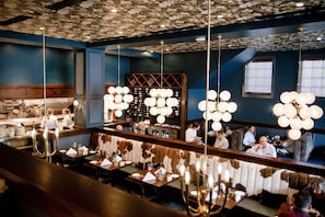 A restaurant with a bar area, tables with candles, and a wine rack in the background. - Stay Lynchburg Iconic Building + Rooftop Dining (Lynchburg)