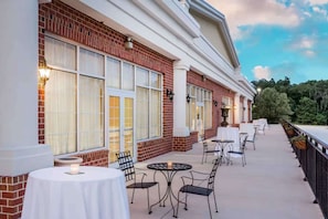 A building with a brick facade, large windows, outdoor seating with tables and chairs, and a railing overlooking a natural landscape. - Near Gettysburg Battlefield + Restaurant & Pool (Gettysburg)