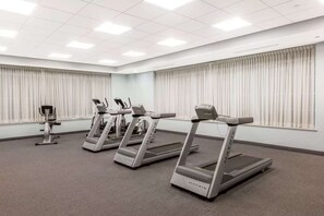 A fitness room with four treadmills, carpeted floor, and large windows with curtains. - Near Gettysburg National Military Park +Restaurant (Gettysburg)