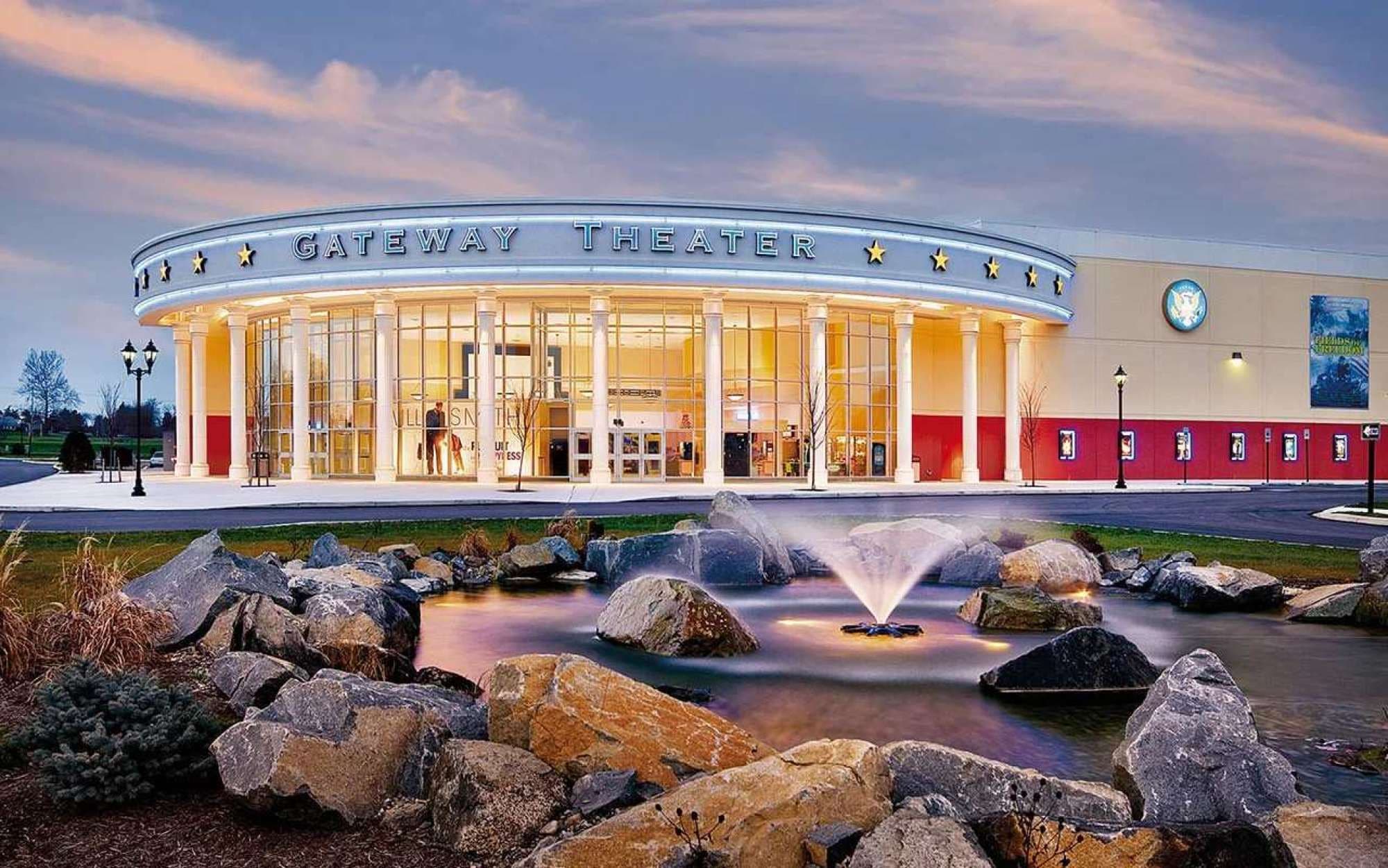 Teatro Gateway con una entrada amplia, una fuente en primer plano y cielo despejado.