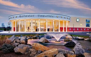 Een Gateway Theater met een brede entree, een fontein ervoor en een heldere lucht.