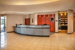 Een hotel receptie met een gebogen balie, een houten deur en een snackbar met planken.