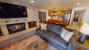 A living room with a fireplace, a sofa, and a television. - 2BR Penthouse w/Kitchen & Balcony + 2 Heated Pools (Vail)