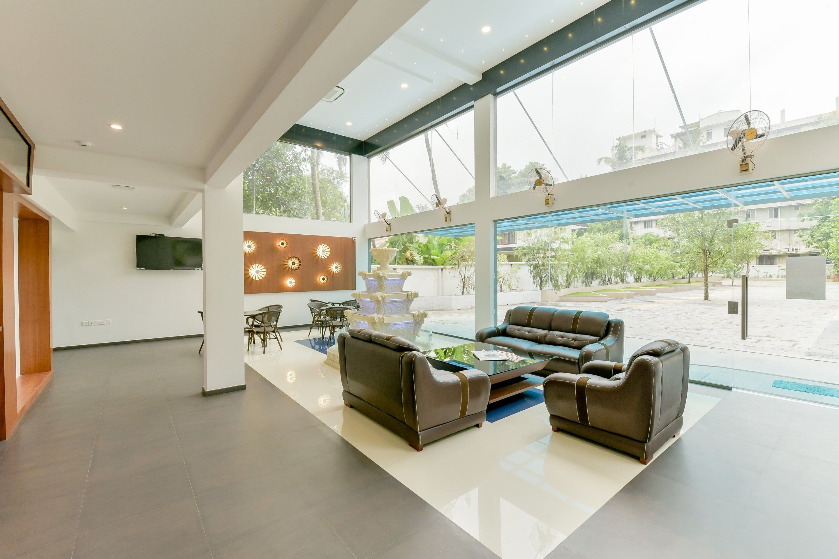 Een ruime lobby met een modern design, met een zithoek met banken en stoelen, een groot raam met uitzicht op het omliggende landschap, en een wandtelevisie.