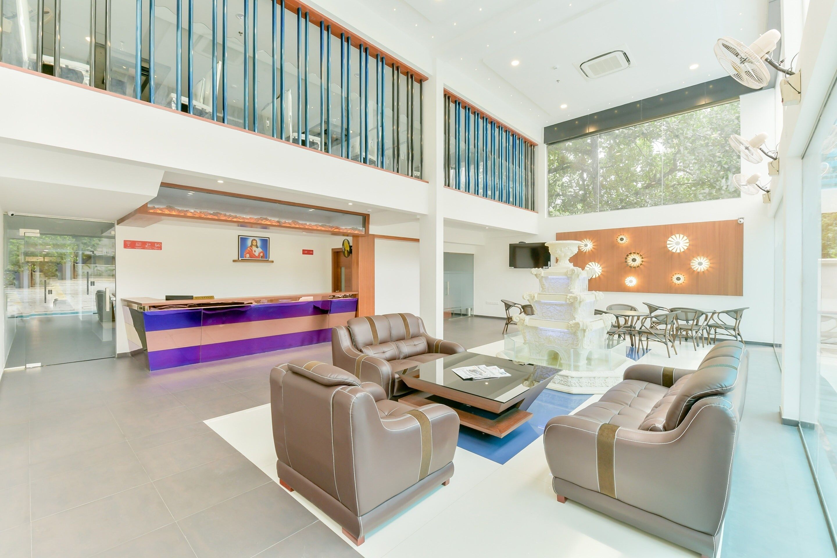 A spacious lobby with a reception desk, leather sofas, a glass coffee table, and a decorative wall with lights.