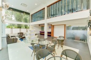 A spacious indoor area with a seating area featuring sofas and chairs, a decorative white fountain, and a glass table. - Super Townhouse Edassery Blue Bells (Aluva)