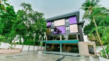 A modern building with a glass facade, surrounded by lush greenery.