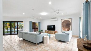 Ein geräumiges Wohnzimmer mit Sofa, Sessel und Fernseher.