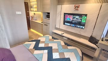 A compact bedroom with a bed, a TV mounted on the wall, and a small bedside table.