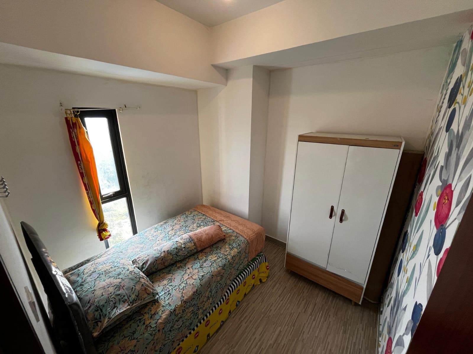 A small, single-bed room with a wardrobe and a window.