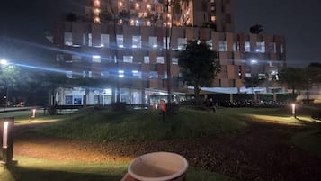 A person holding a cup, with a modern building in the background.