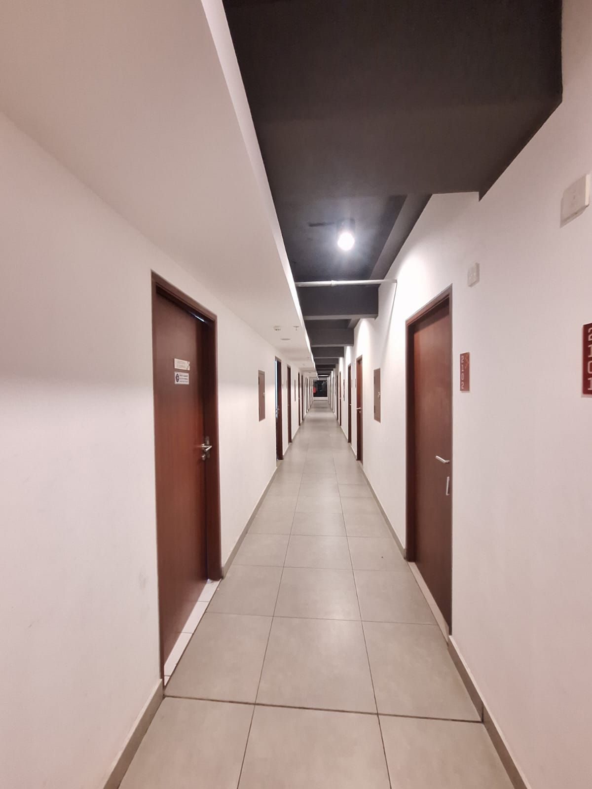 A long, narrow hallway with doors on both sides, leading to individual rooms.
