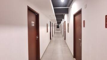 A long, narrow hallway with doors on both sides, leading to individual rooms.