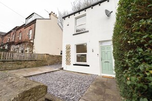 A residential property with a white exterior, a green door, and a gravel driveway. - Peaceful Returns - 2 Bed House Near Roundhay Park (Leeds)