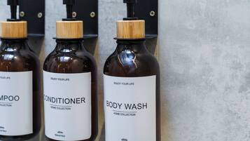 Three bottles of shampoo, conditioner, and body wash on a wall.