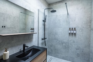 Une salle de bain moderne avec un lavabo noir, une douche à parois de verre et un grand miroir.