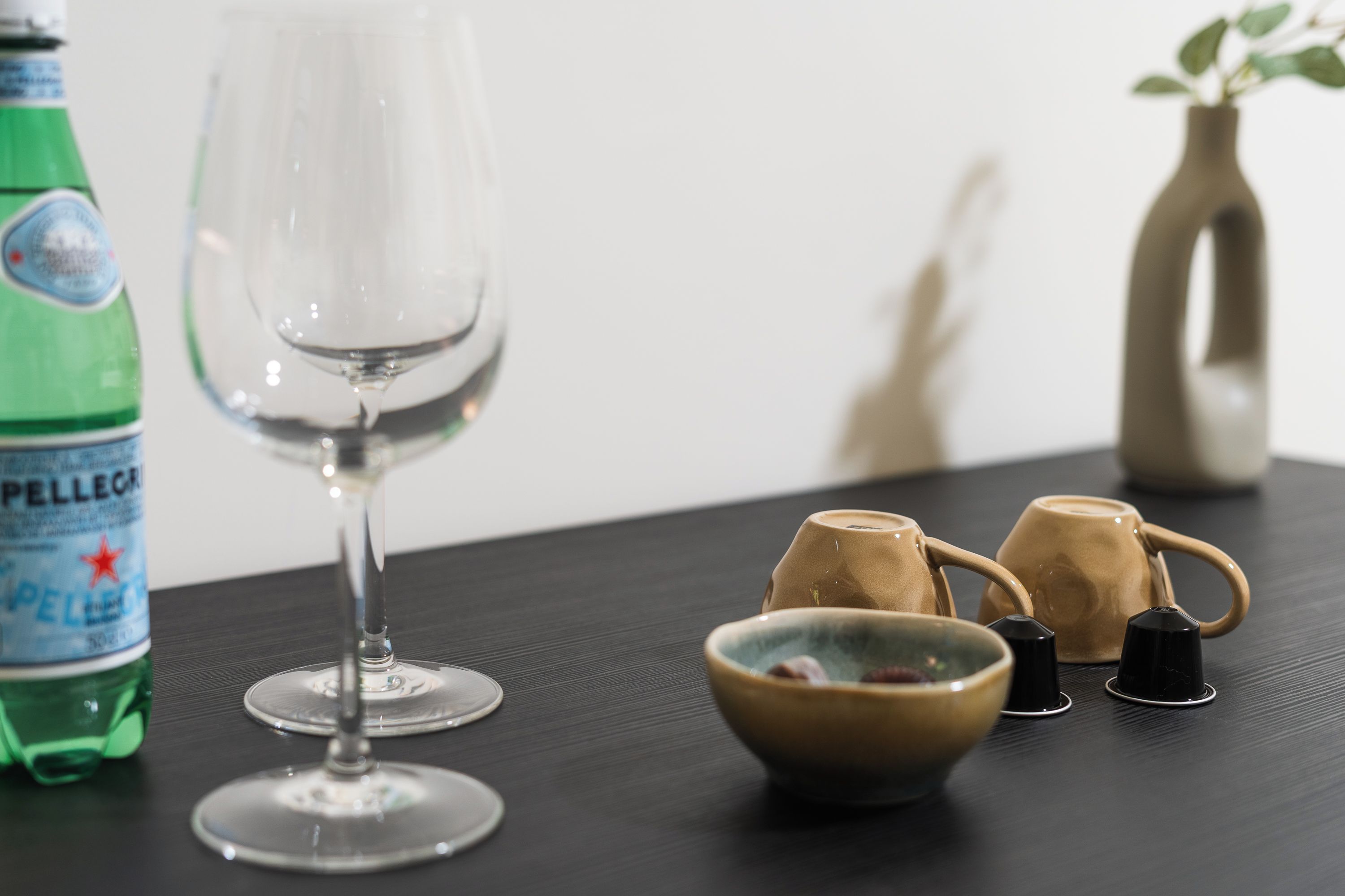 Ein Tisch mit einer Flasche, einem Weinglas, einer Schüssel und zwei Tassen.