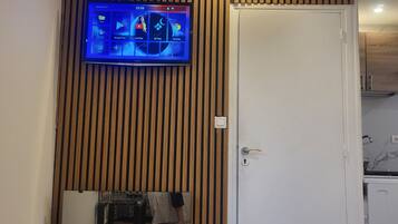 A flat-screen TV mounted on a wooden wall above a white door, displaying a digital interface with various app icons.