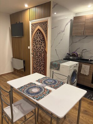 Una cocina funcional con lavadora, armarios de madera y una puerta decorativa.