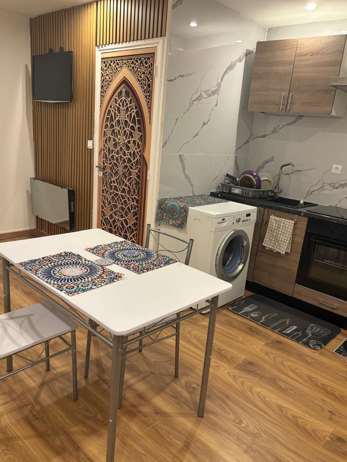 Een kleine keuken met een wasmachine, een magnetron en een spoelbak.