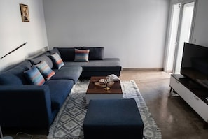 A living room with a sectional sofa, a coffee table, and a television. - sandra 27 (Tunis)